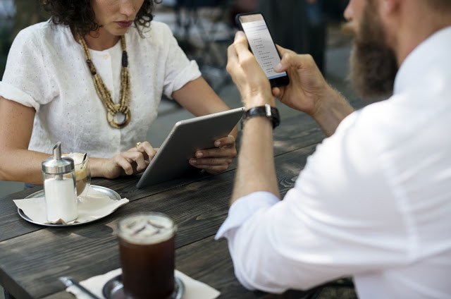 two people at cafe using smartphone and tablet